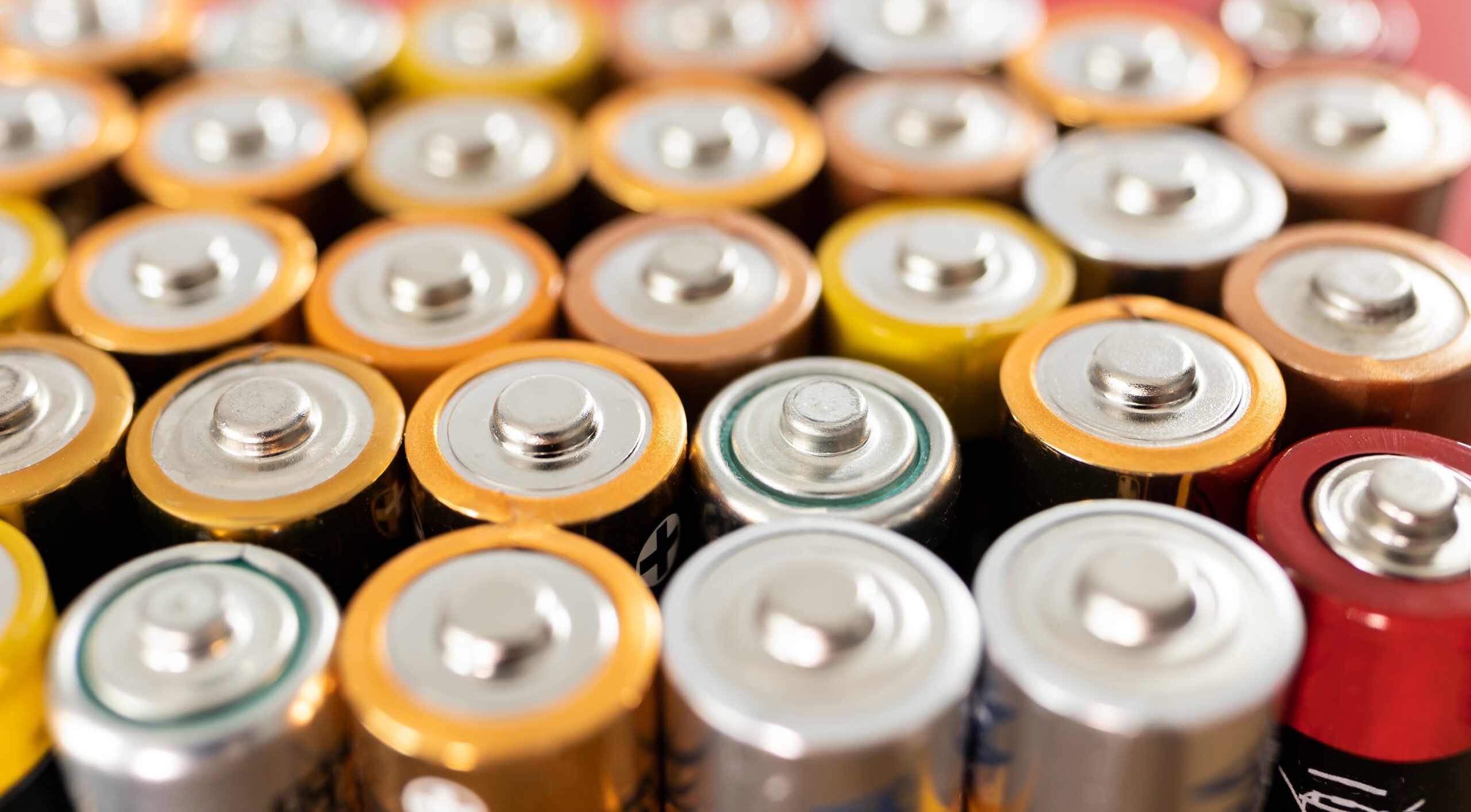Close-up of assorted batteries showing positive terminals.