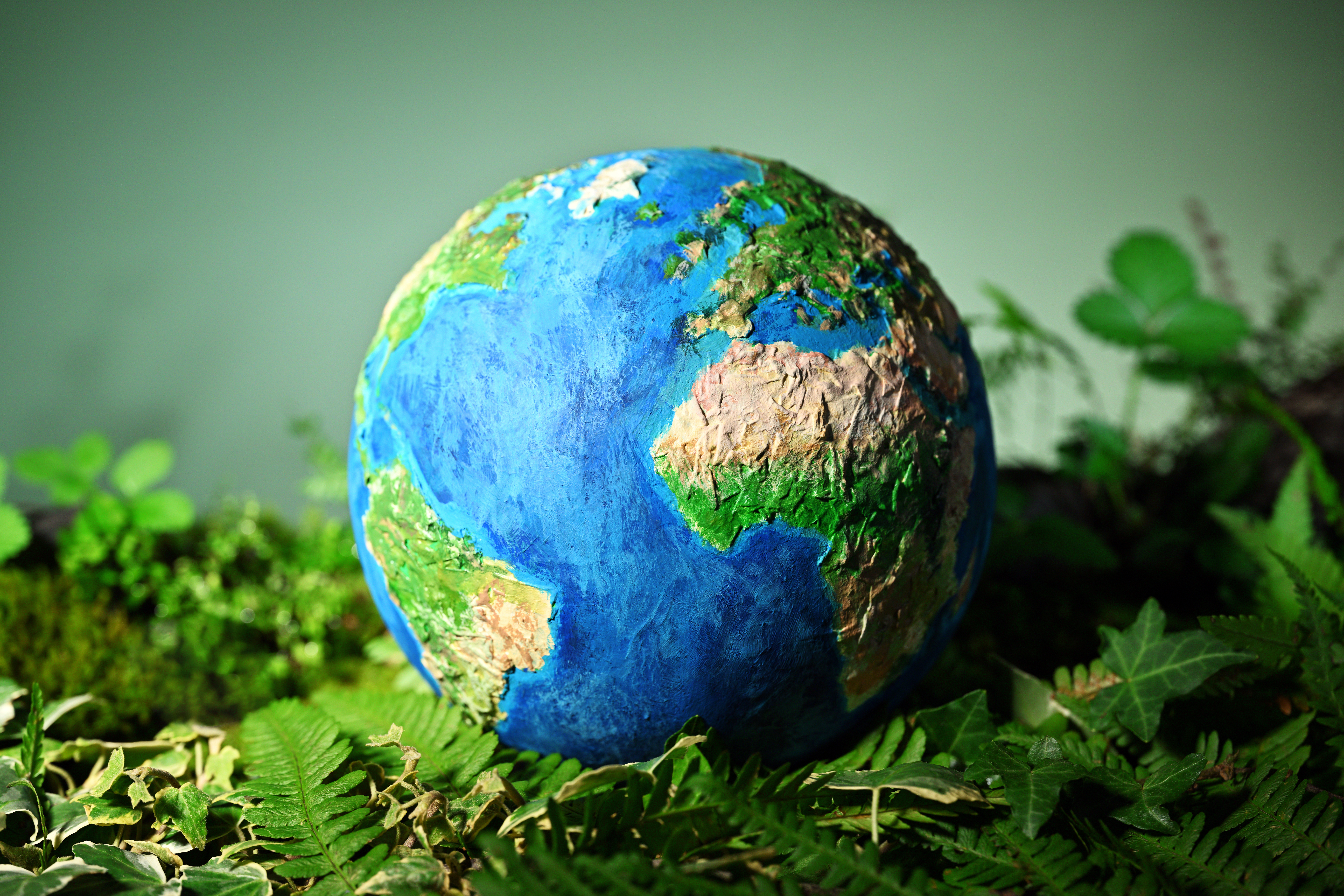 Paper mache earth sitting on top of green leaves.