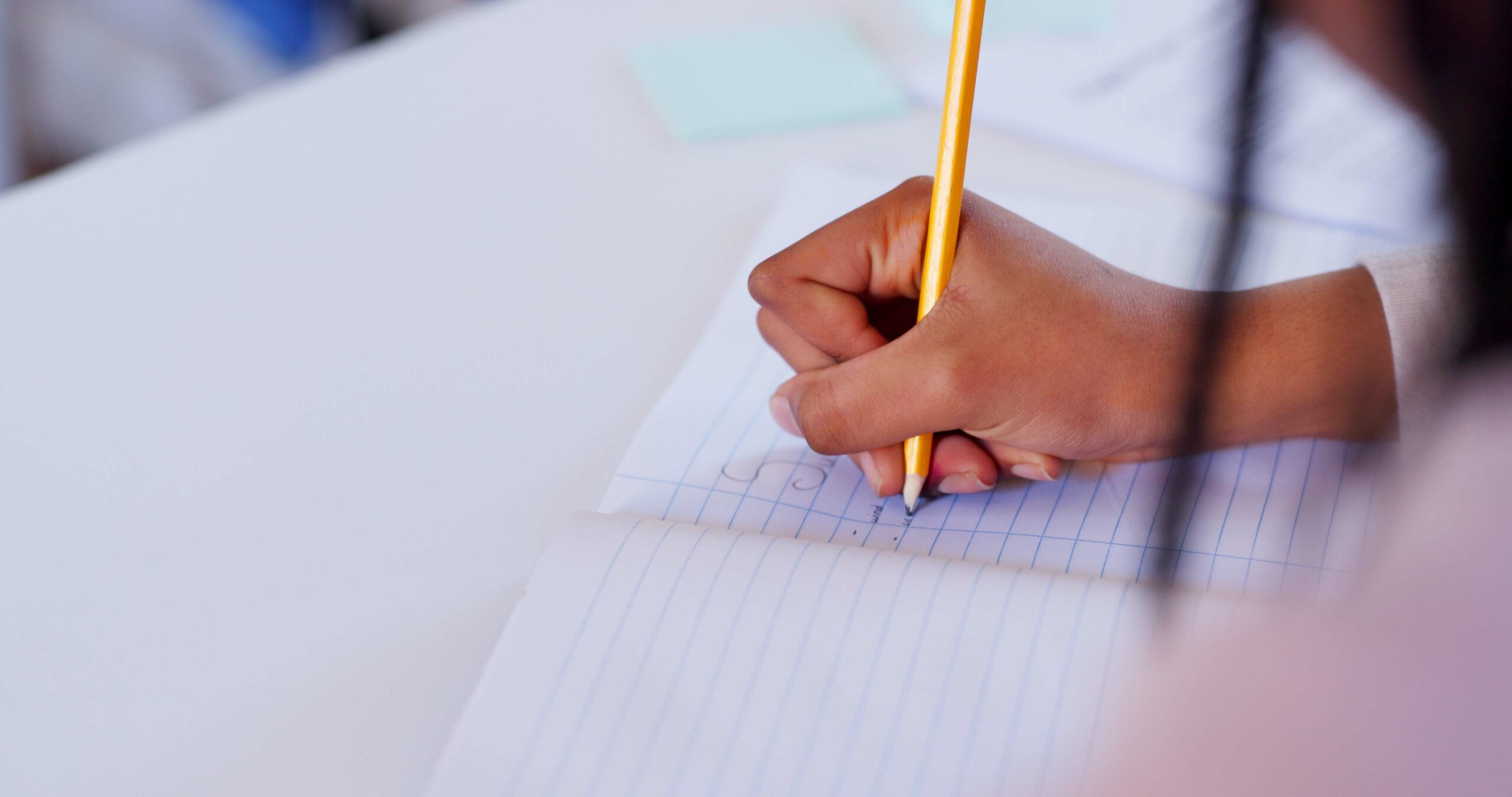 Student writing notes in a notebook.