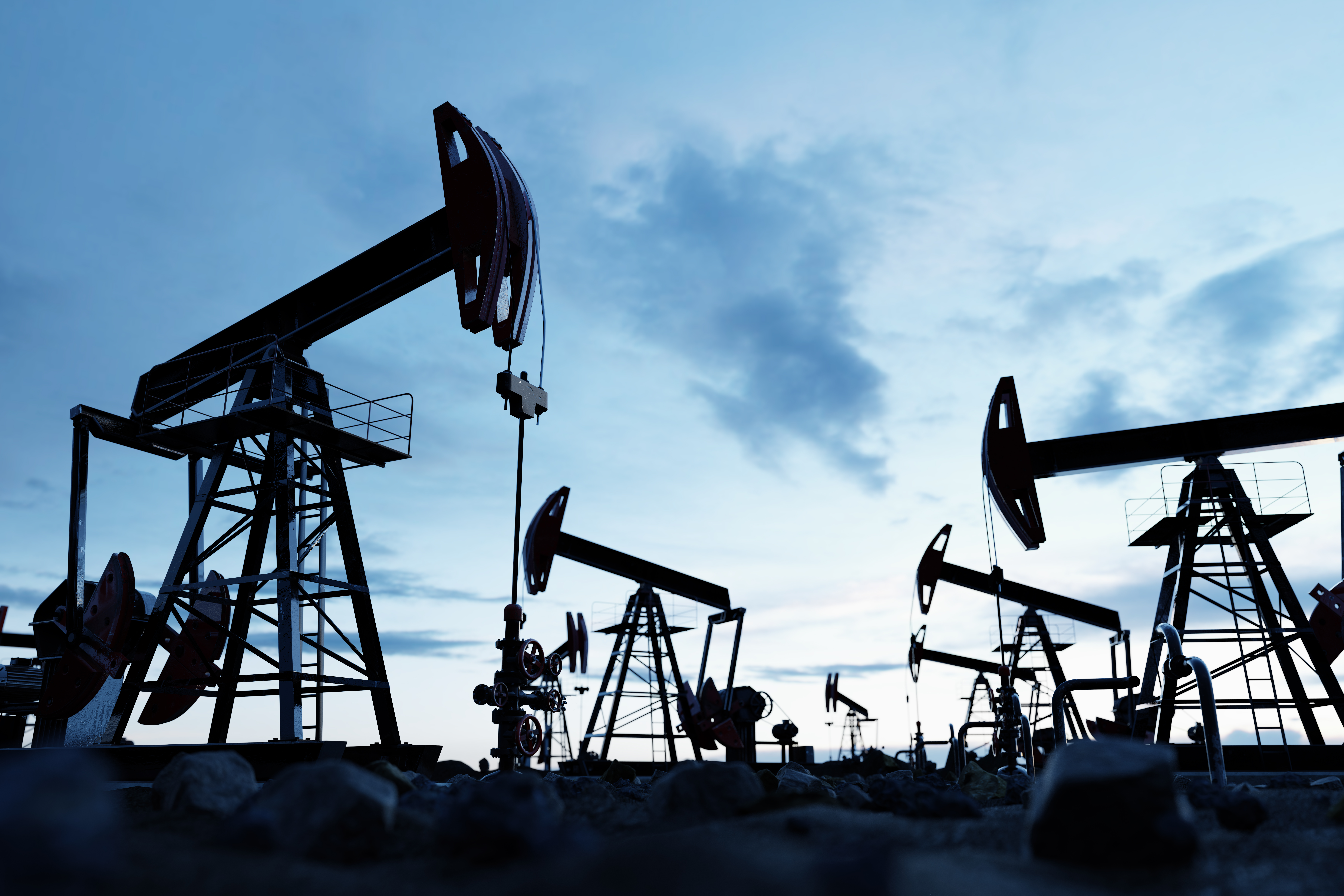 Oil pumpjacks working in a field at dusk.